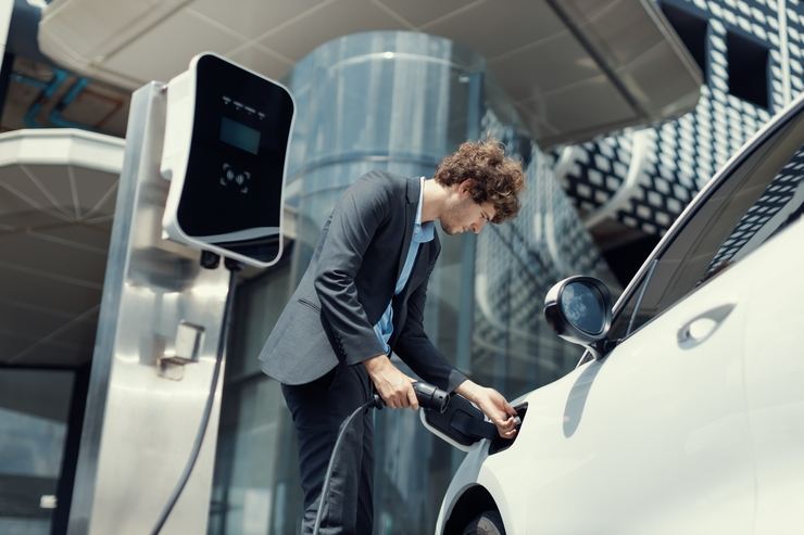 Un uomo ricarica la propria auto elettrica