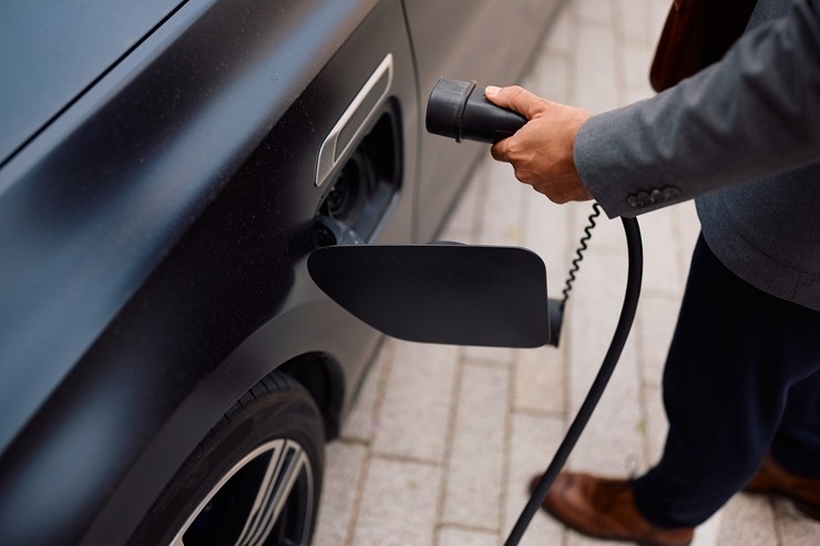 Un uomo ricarica un'auto elettrica